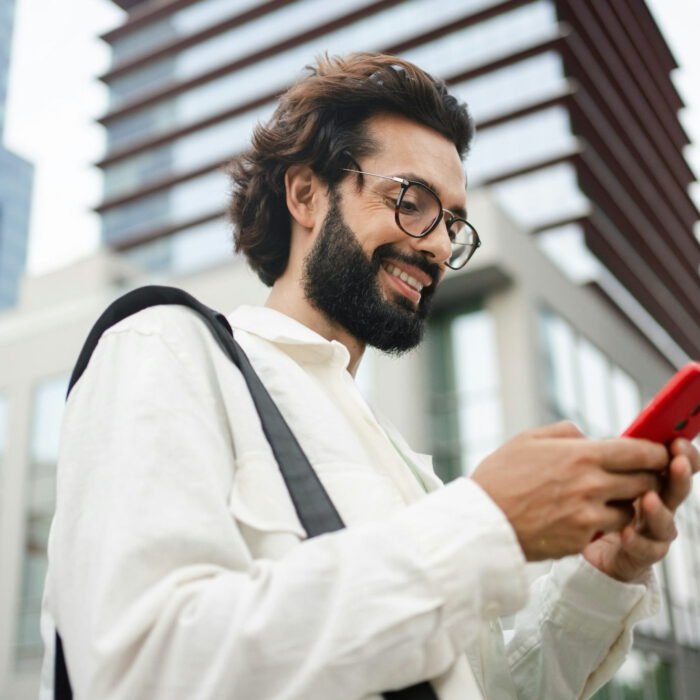 Happy satisfied man using cell phone app in the city -Young professional reading good news