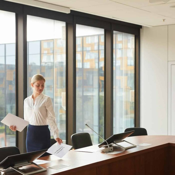 Beautiful Female Assistant Laying Out Documents in Conference Room
