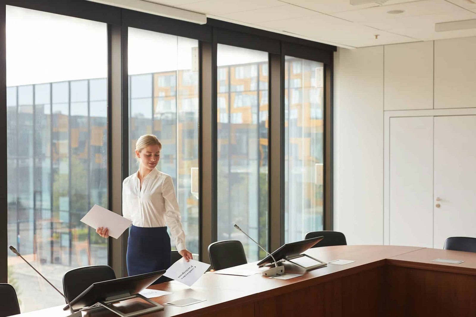 Beautiful Female Assistant Laying Out Documents in Conference Room