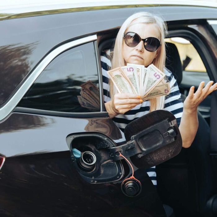 desperate woman hold cash dollar bills in to car with an open tank, concept of rising fuel prices